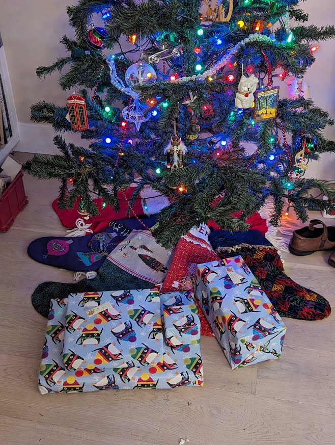 Scene of the foot of a Christmas tree with four presents wrapped in winter penguins themed paper
