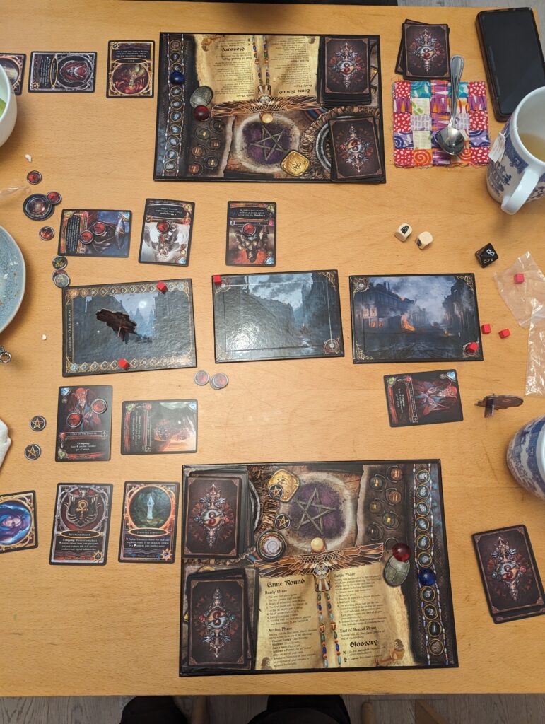 Table with two player boards from Sorcerer, two battlefields already defeated with one player having won one battlefield each.